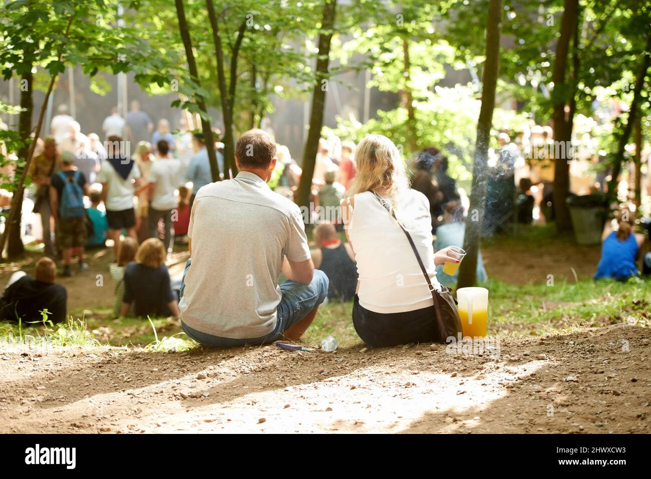 Etwas Zeit im Freien verbringen. Rückansicht eines Paares, das bei einer Veranstaltung im Freien unter den Bäumen sitzt. Stockfoto