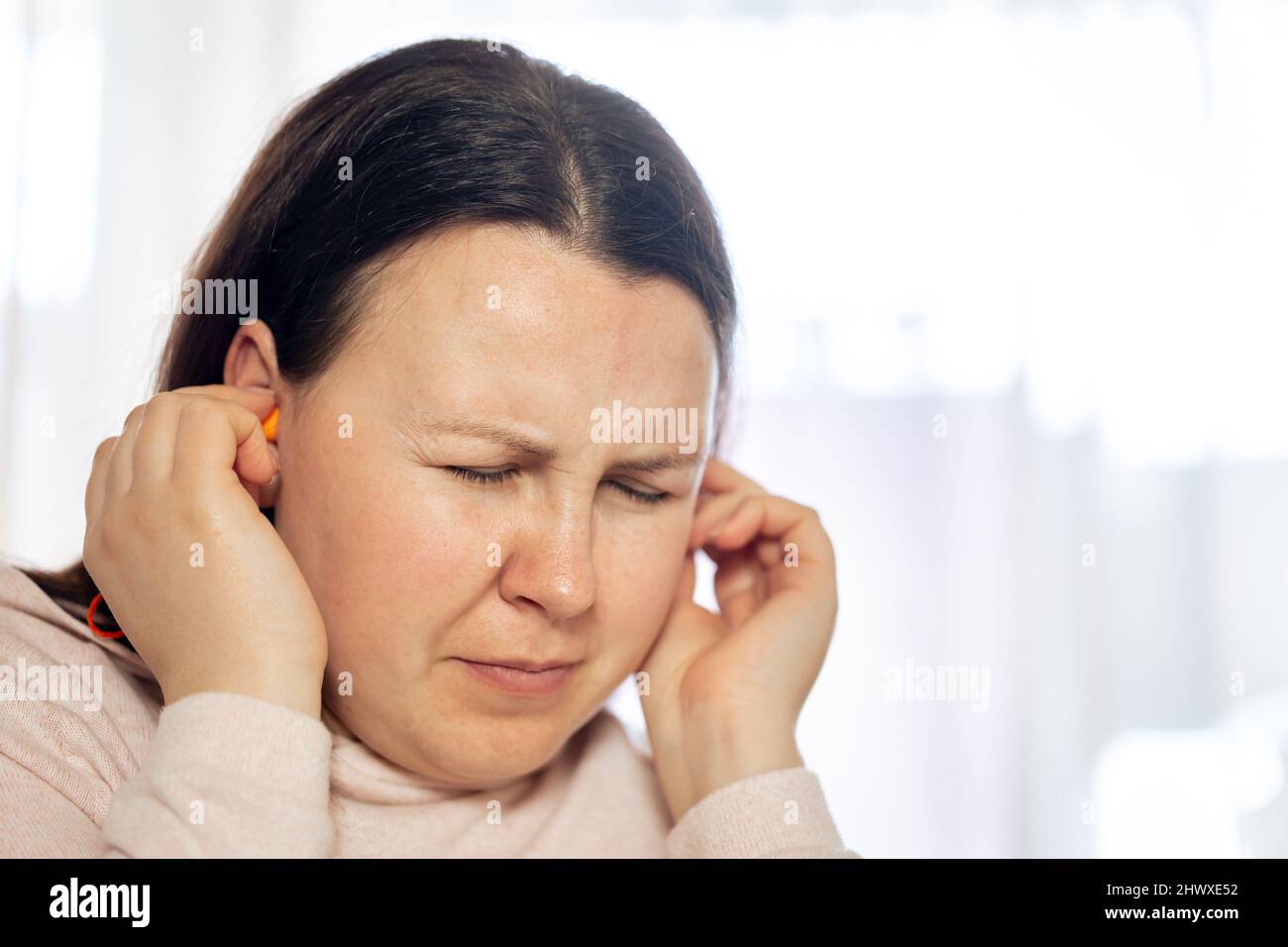 Junge Frau, die an Tinnitus-Krankheit der Zivilisation leidet, Gesundheitskonzept Stockfoto