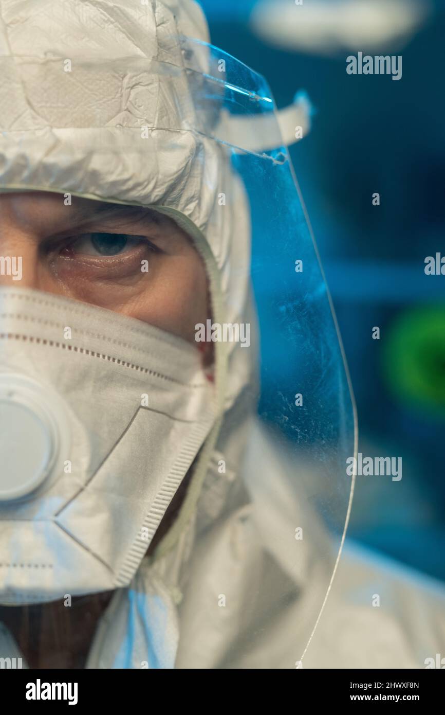 Teil des Gesichts eines männlichen Wissenschaftlers in Schutzhüllen, Atemschutzmaske und Bildschirm, der vor der Kamera im modernen wissenschaftlichen Labor steht Stockfoto