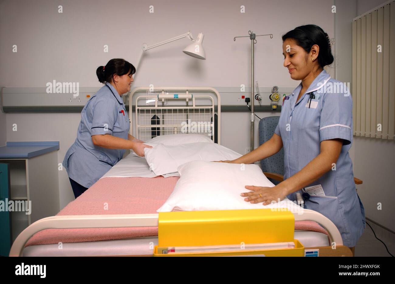 Zwei Krankenschwestern machen ein Bett auf einer Krankenstation. (MODELL FREIGEGEBEN) Stockfoto