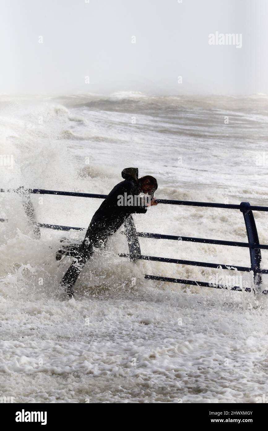 England, East Sussex, Hastings, man trotzt den wilden Wellen, die die Promenade während des Sturms schlagen. Stockfoto