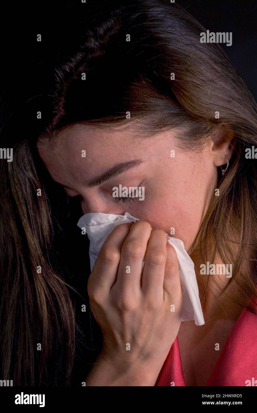 Junge Frau niest in ein Gewebe (MODELL FREIGEGEBEN) Stockfoto