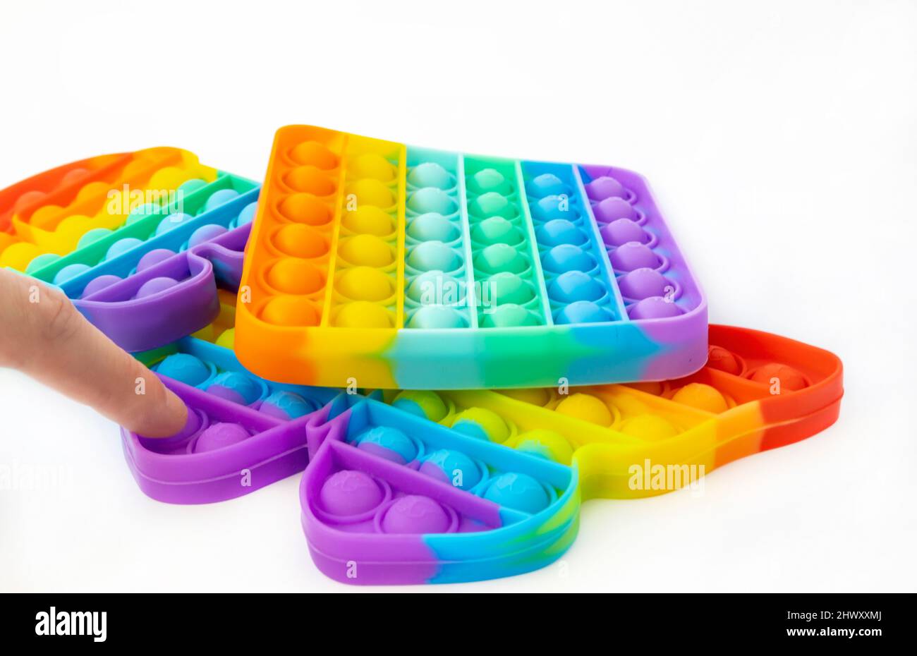 Anti-Stress-Spiel Pop it. Er presst mit seinem Finger bunte Blasen auf ein Schmetterlingsspielzeug. Stockfoto