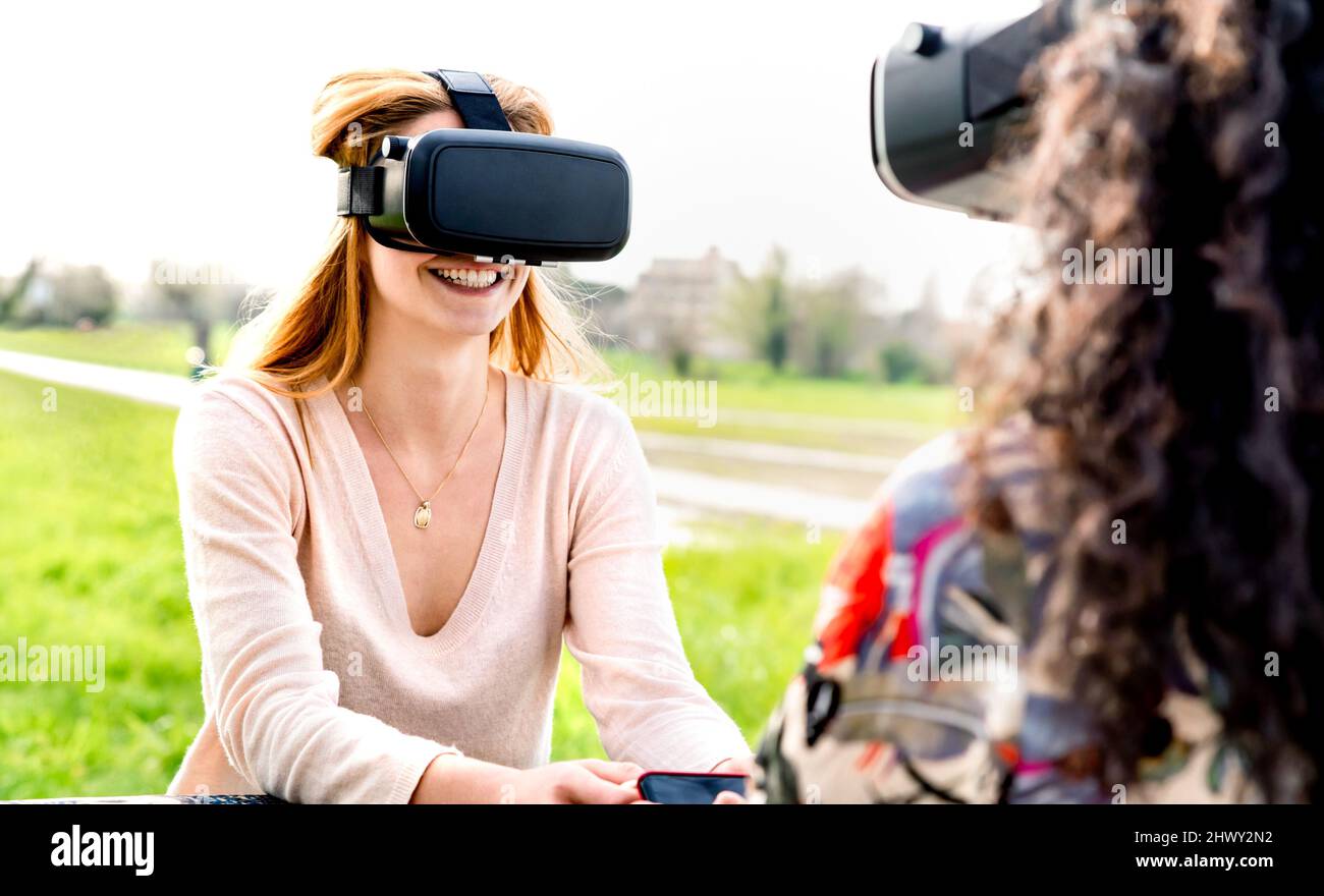 Junge Frauen spielen auf vr im Freien - Virtual Reality und Wearable Tech-Konzept mit glücklichen Mädchen Spaß zusammen mit Headset-Brille - Gene Stockfoto