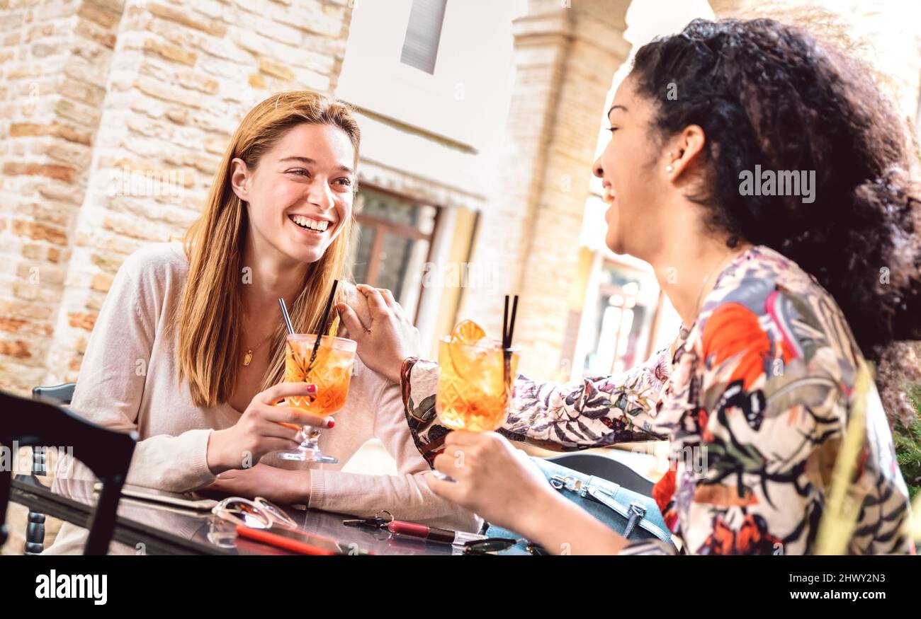 Trendige Frauen trinken Cocktails an der Open Air dehor Bar zur Happy Hour - Life Style Konzept mit multirassischen Freundinnen, die echten Spaß zusammen haben Stockfoto