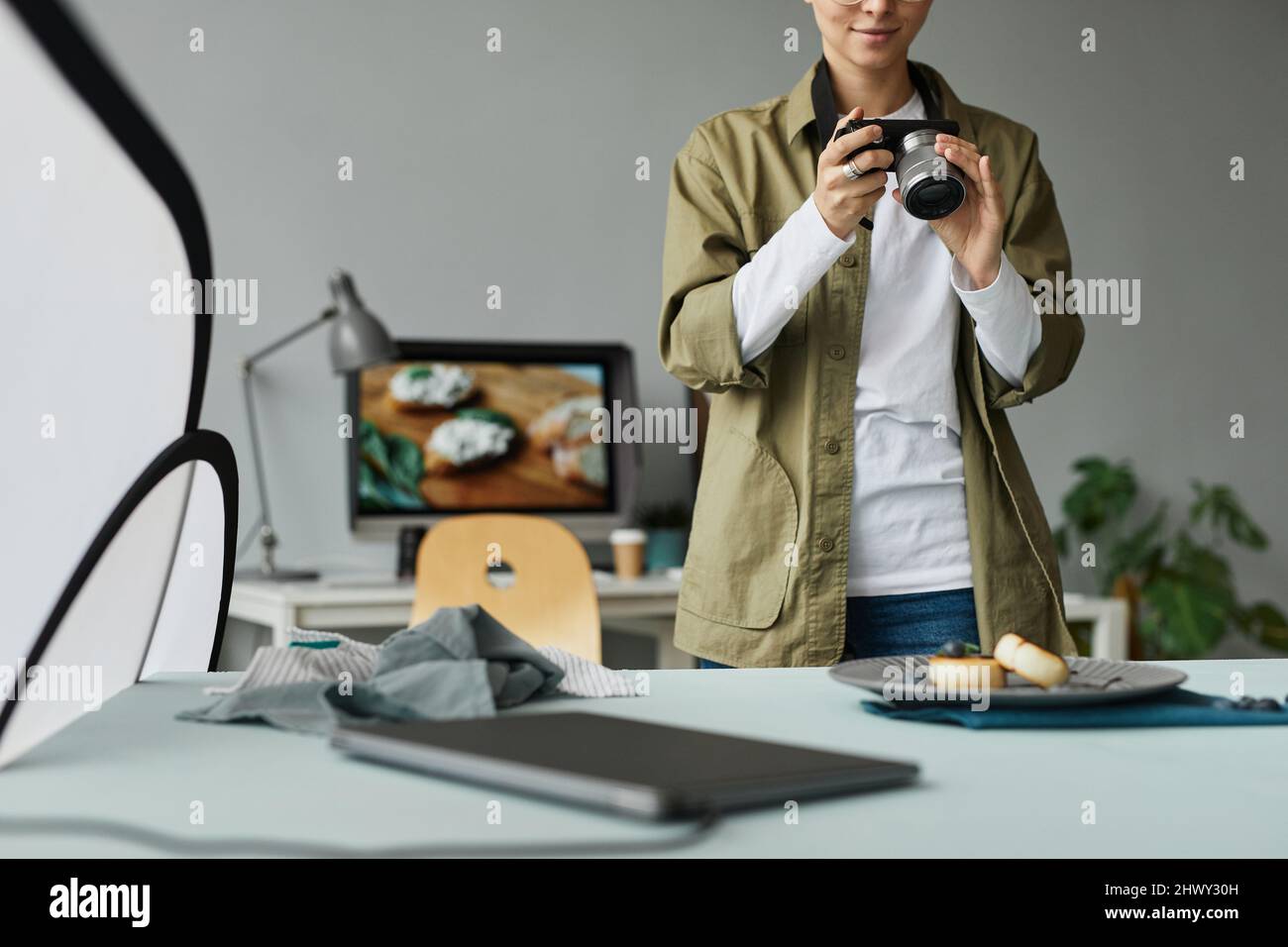 Beschnittenes Porträt eines jungen Food-Fotografen, der im Studio fotografiert, digitales Creator-Konzept Stockfoto