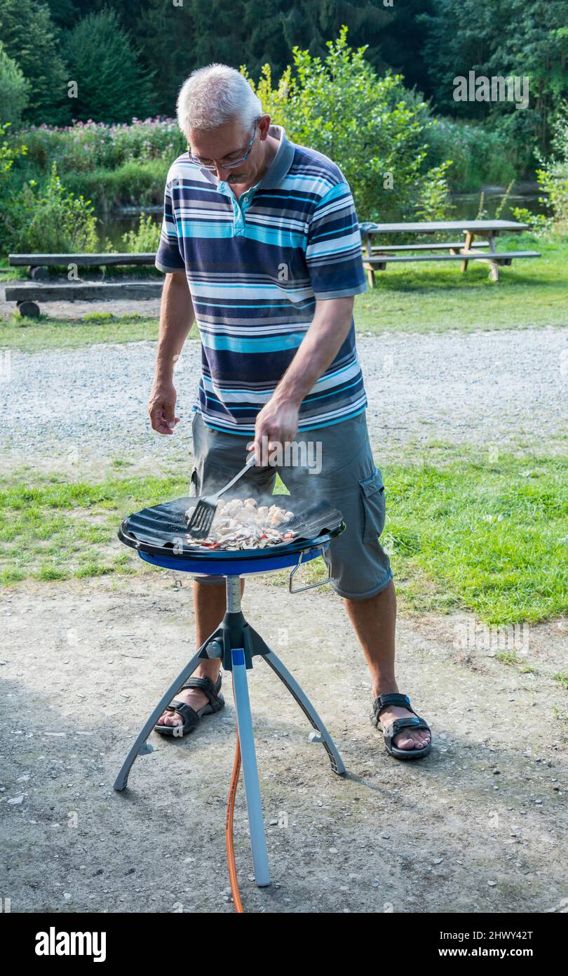 Mann, der auf dem Campingplatz kocht Stockfoto