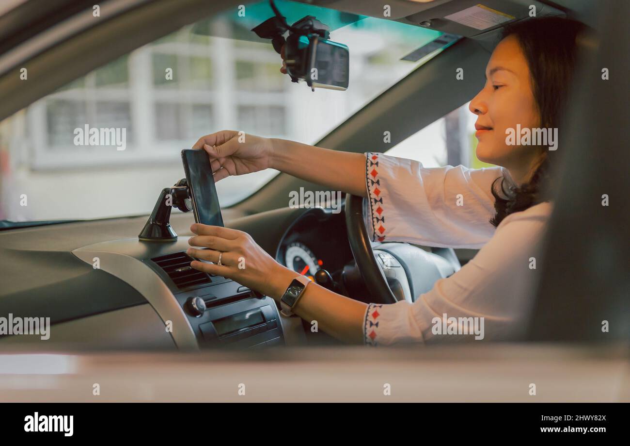 Frau Fahrer Hand passen Handy in Standhalter Richtung. Stockfoto
