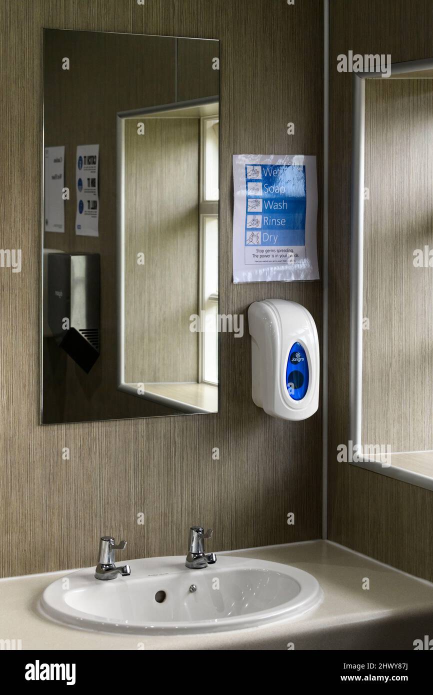 Waschräume oder WC-Innenraum (Waschbecken, 2 heiß- und Kaltwasserhähne, Handwäsche-Beratung Erinnerung, Reflexion im Spiegel,) - Bolton Abbey, Yorkshire, England, UK. Stockfoto