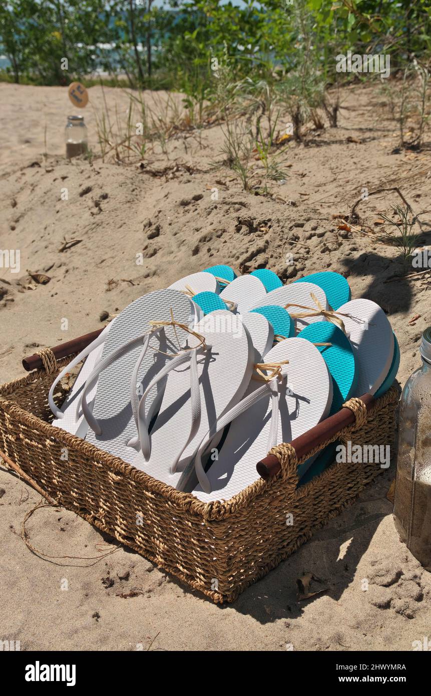 Korb voller Sandalen in Weiß und Türkisblau am Strand Stockfoto