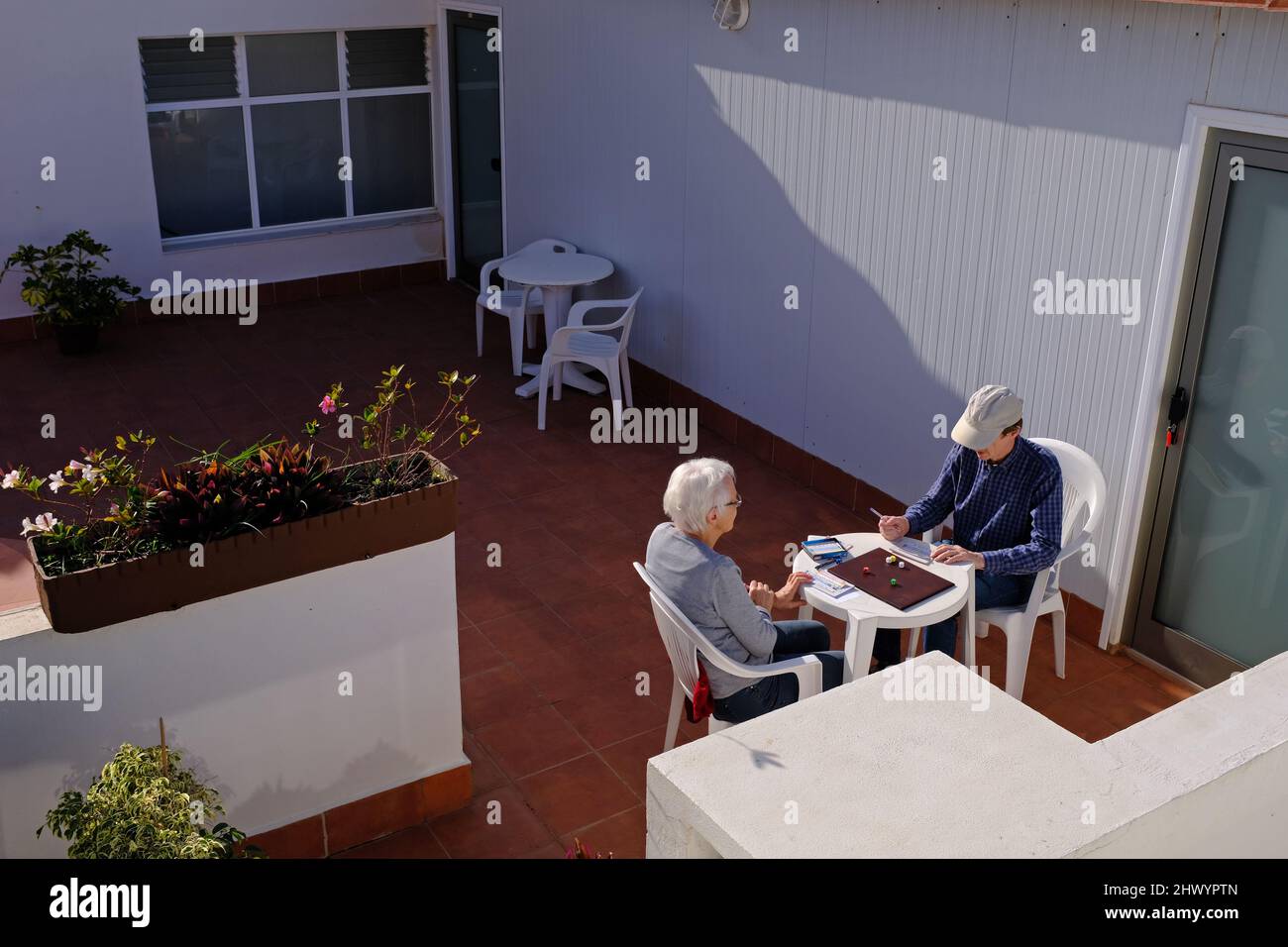 Zwei ältere Menschen spielen in einem Hotel ein würfelbasiertes Spiel. Stockfoto