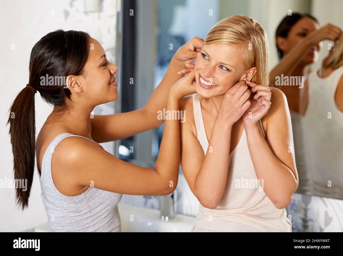 Ein paar Funkeln aufsetzen. Aufnahme einer jungen Frau, die ihrem Freund hilft, ihre Ohrringe einzuhängen. Stockfoto