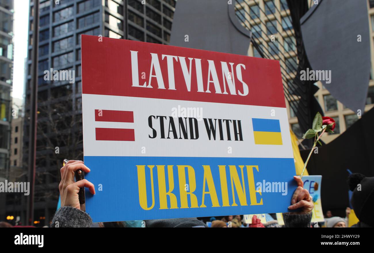 Die Letten stehen mit einem Protestschild mit Flaggen auf dem Daley Plaza in Chicago Stockfoto