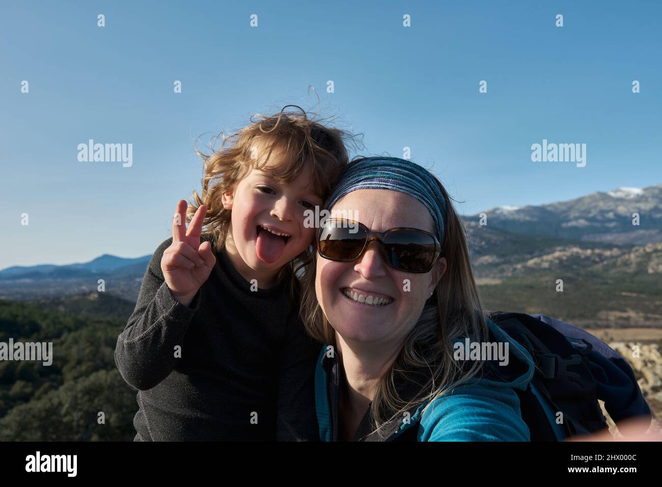 Eine Mutter und ein Sohn machen Selfies in der Natur, der Junge fratzt und zeigt seine Zunge. Stockfoto