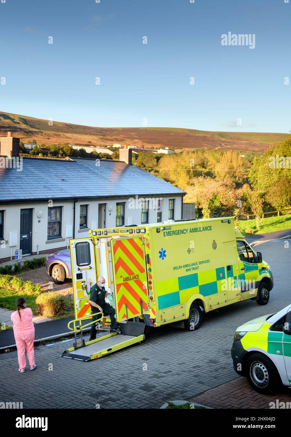 Sanitäter bringen einen Patienten in ihren Krankenwagen, nachdem er den Patienten in seinem Haus in der Nähe von Pontypool, S. Wales, Großbritannien, untersucht hat Stockfoto