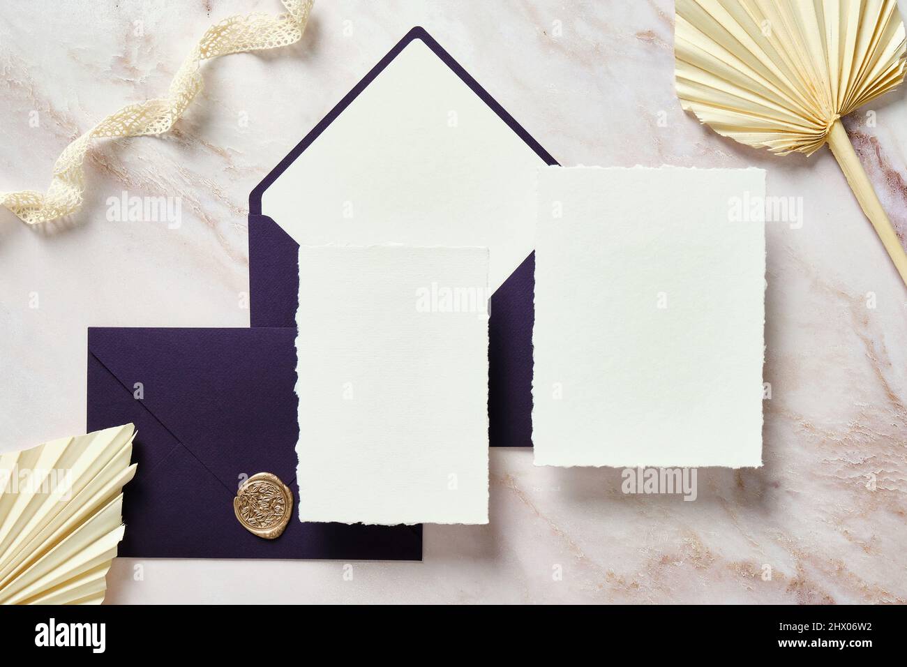 Elegantes Hochzeitspapier-Set. Vorlagen für Hochzeitseinladungskarten, violette Umschläge, Seidenband, getrocknete Blumen auf Stein-Schreibtisch. Stockfoto