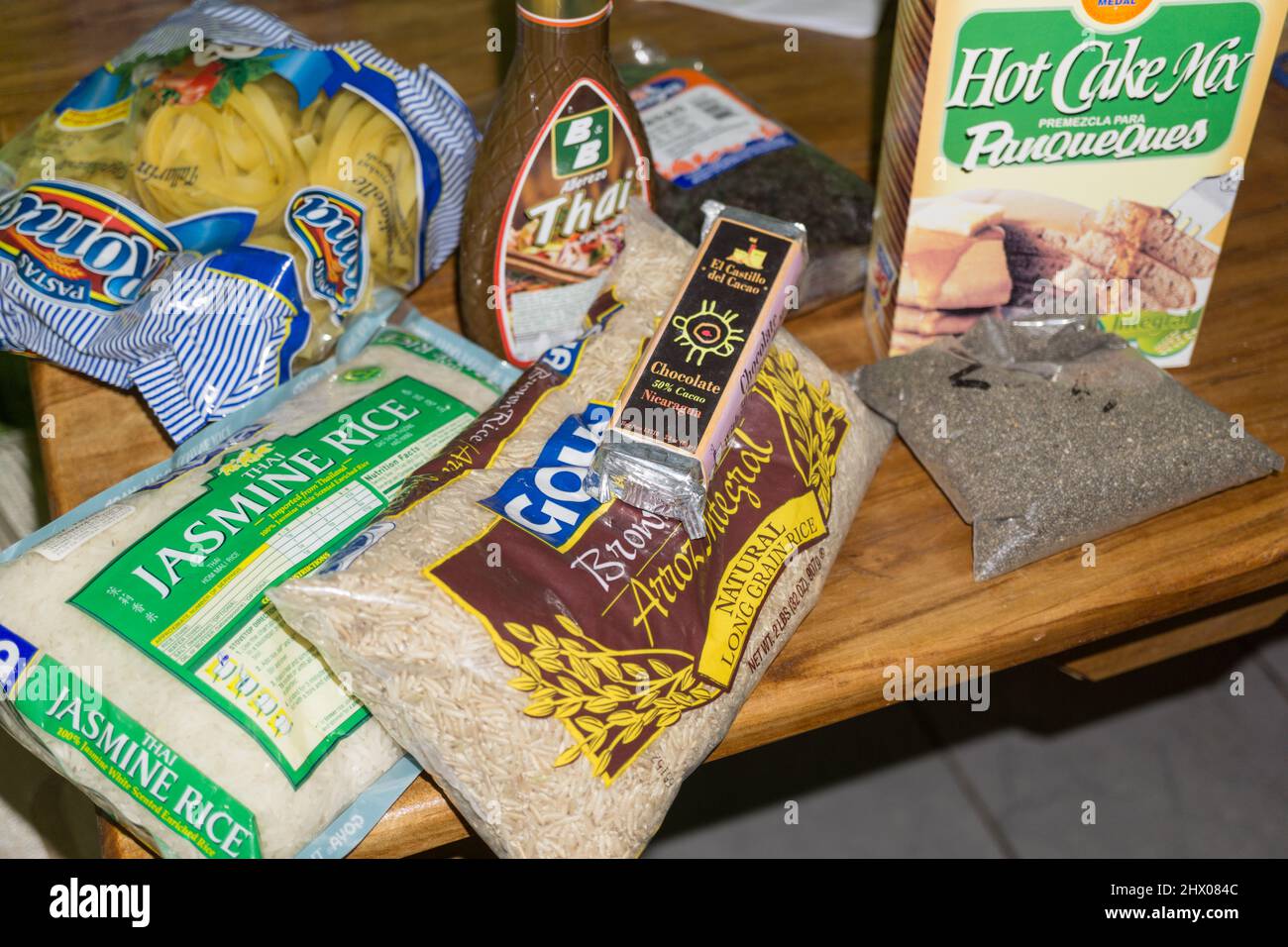 Einkauf im Supermarkt zu schleppen ist ein expat zeigt die beiden Nicaraguanischen verpackte Lebensmittel, einschließlich Chia Samen, und eingeführten Reissorten und Thai Sauce. Stockfoto