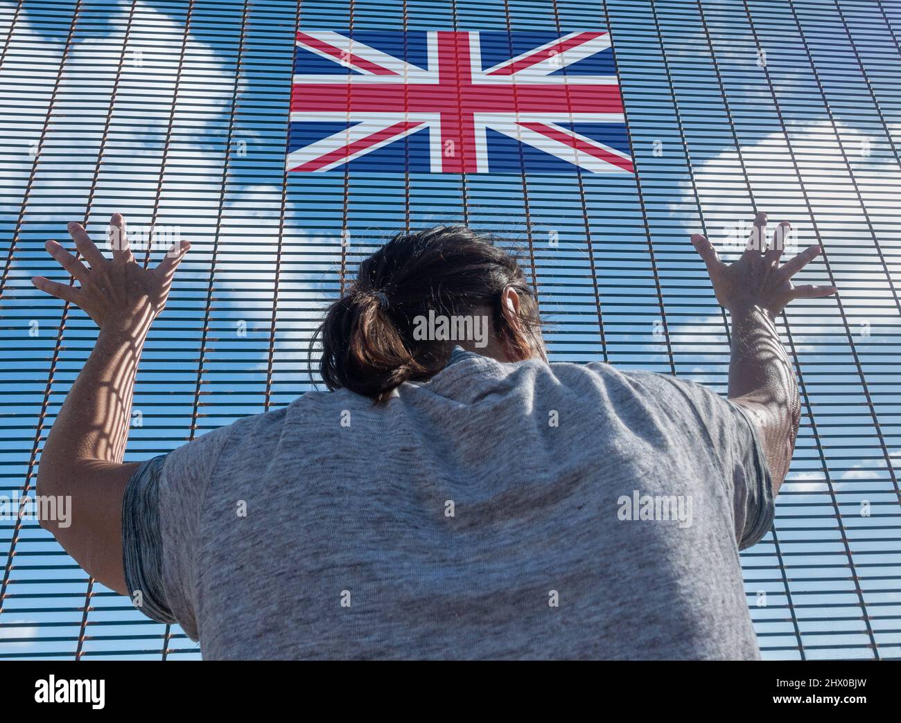 Rückansicht einer Frau bei der Grenzzaunkontrolle mit britischer Flagge. Britische Einwanderung, Visapolitik, Ukraine, Russland Konflikt Flüchtling, Brexit, EU-Grenze... Konzept Stockfoto