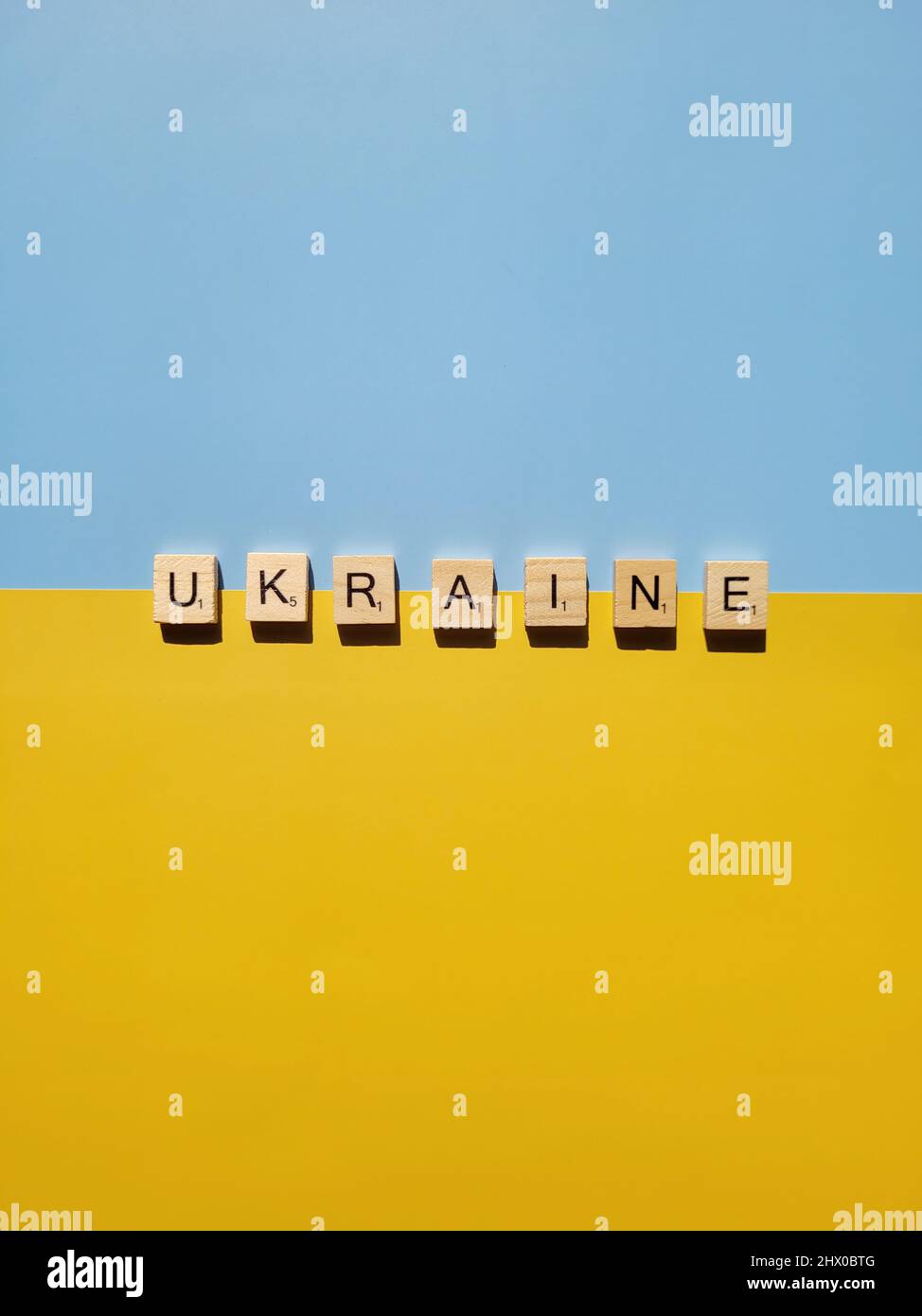 Wörter auf hölzernen Buchstaben auf gelbem, blauem Hintergrund aus nächster Nähe. Flach liegend. Konzept der Freiheit und Unterstützung der Ukraine. Protestaktion. Krieg beenden. Stockfoto