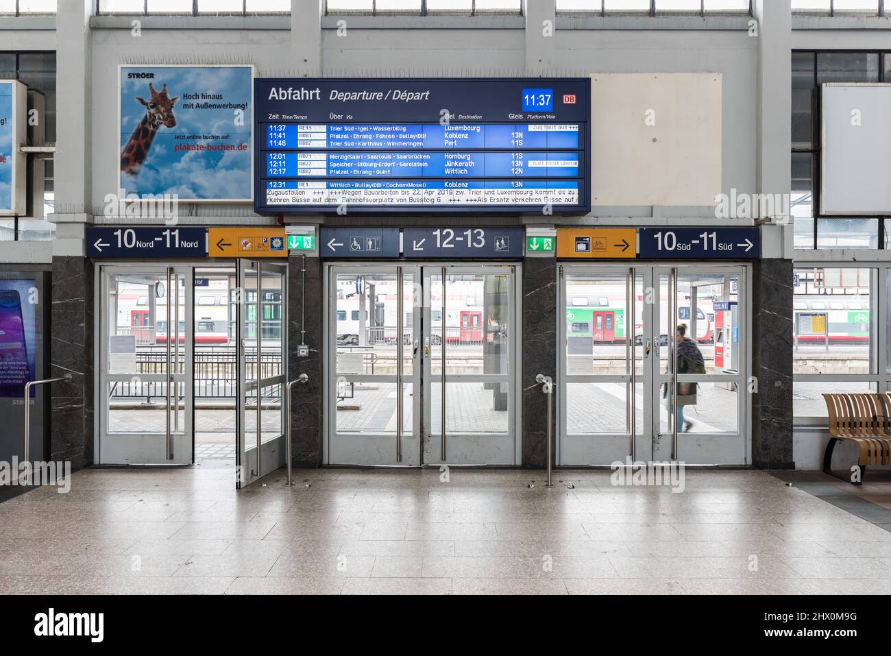 Trier, Rheinland-Pfalz - Deutschland - 04 15 2019 - Innenansicht des Trierer Hauptbahnhofs mit den Eingangstüren und dem elektronischen Fahrplanauszug Stockfoto