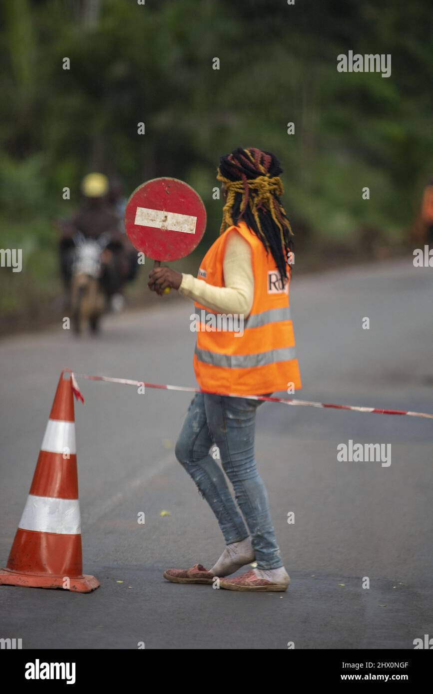 Junge Arbeiterin in einer orangefarbenen Weste, die ein No-Entry-Zeichen hochhält Stockfoto