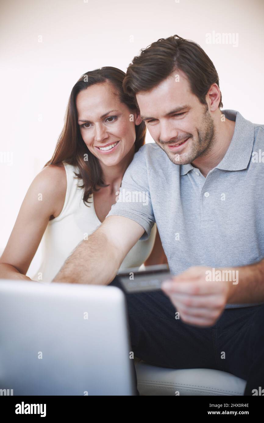 Online-Banking – schnell und einfach. Aufnahme eines jungen Mannes, der online Bankgeschäfte macht, während seine Frau neben ihm sitzt. Stockfoto