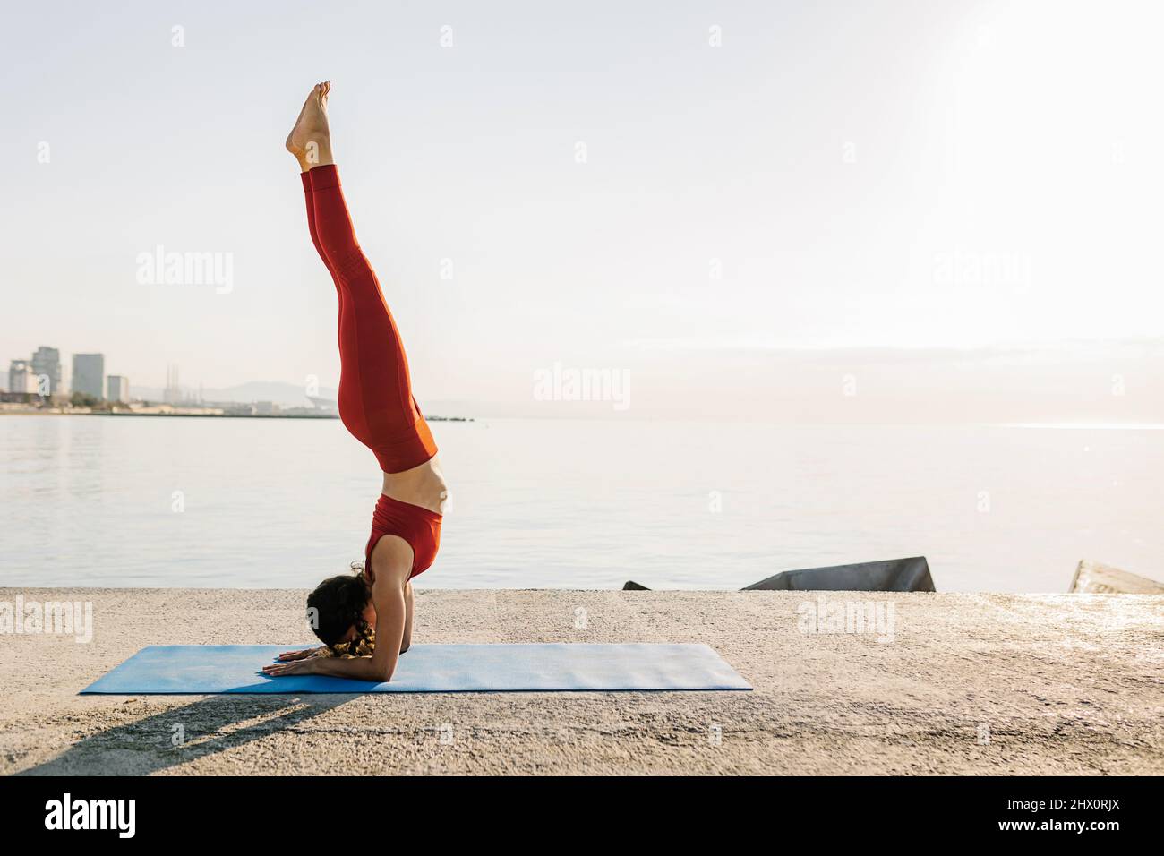 Junge Erwachsene Frau, die im Freien Yoga praktiziert Stockfoto