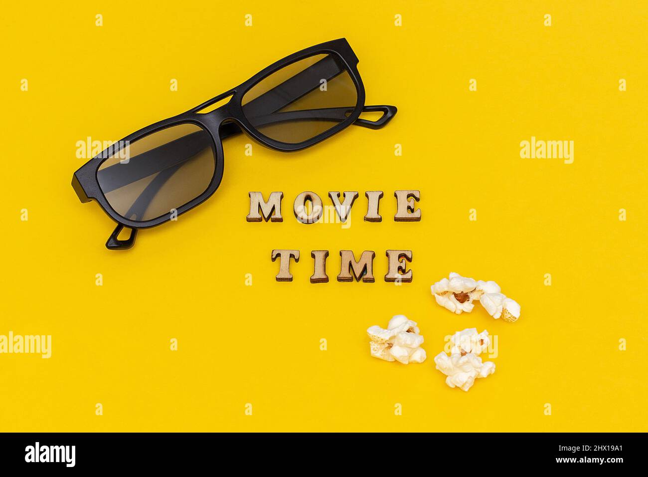 3D Gläser, Popcorn und Text Movie Time auf gelbem Papierhintergrund. Draufsicht Template Konzept Kino Film und Unterhaltung. Stockfoto