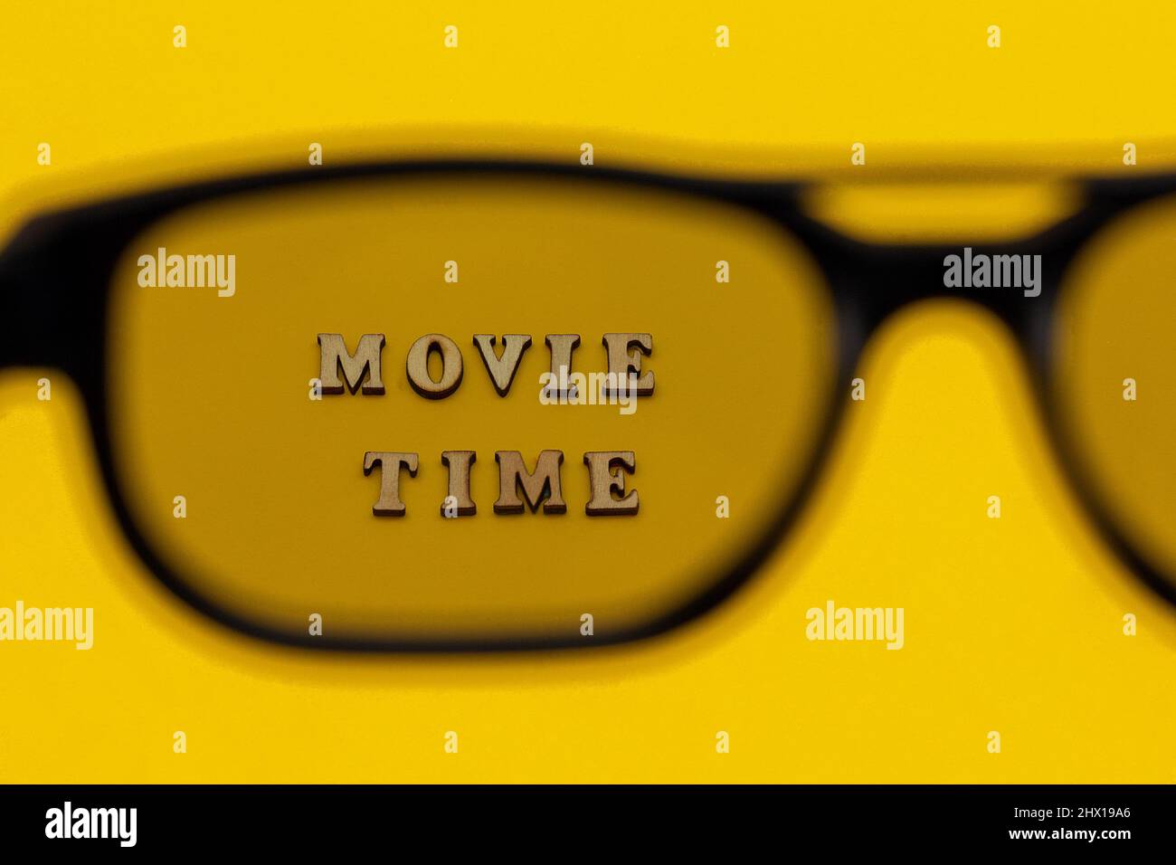 Konzentrieren Sie sich auf den Text Filmzeit durch 3D Gläser auf gelbem Papierhintergrund. Konzept Kinofilm und Unterhaltung. Stockfoto