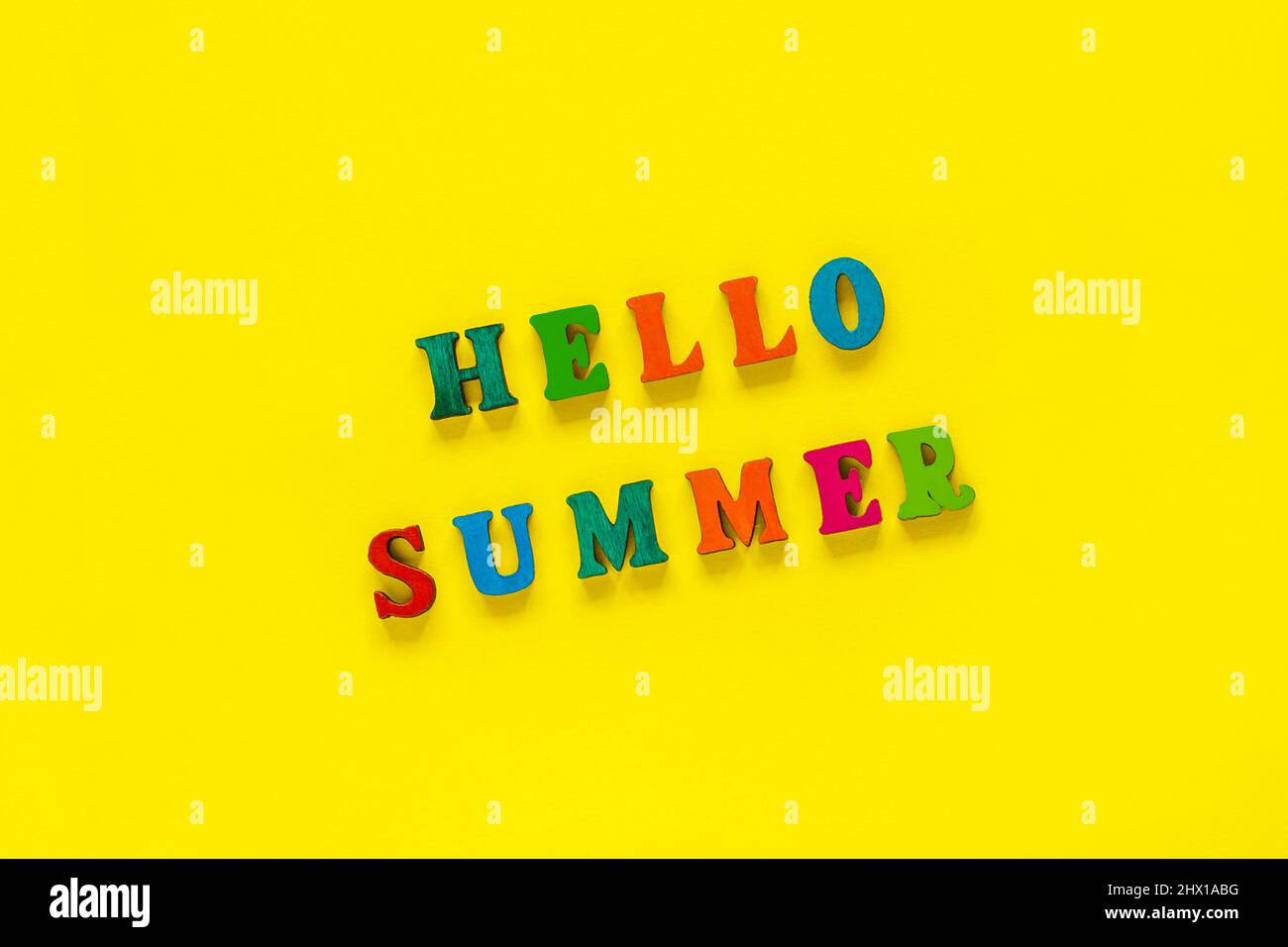 Inschrift Hello Summer aus bunten Buchstaben auf gelbem Hintergrund, Nahaufnahme Draufsicht Kopierbereich Stockfoto