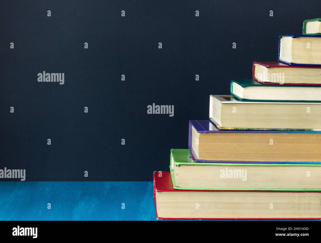 Stapeln Sie Stufen von alten Büchern auf dem Hintergrund schwarze Tafel, kopieren Raum, Konzept Bildung, Weg zum Wissen Stockfoto
