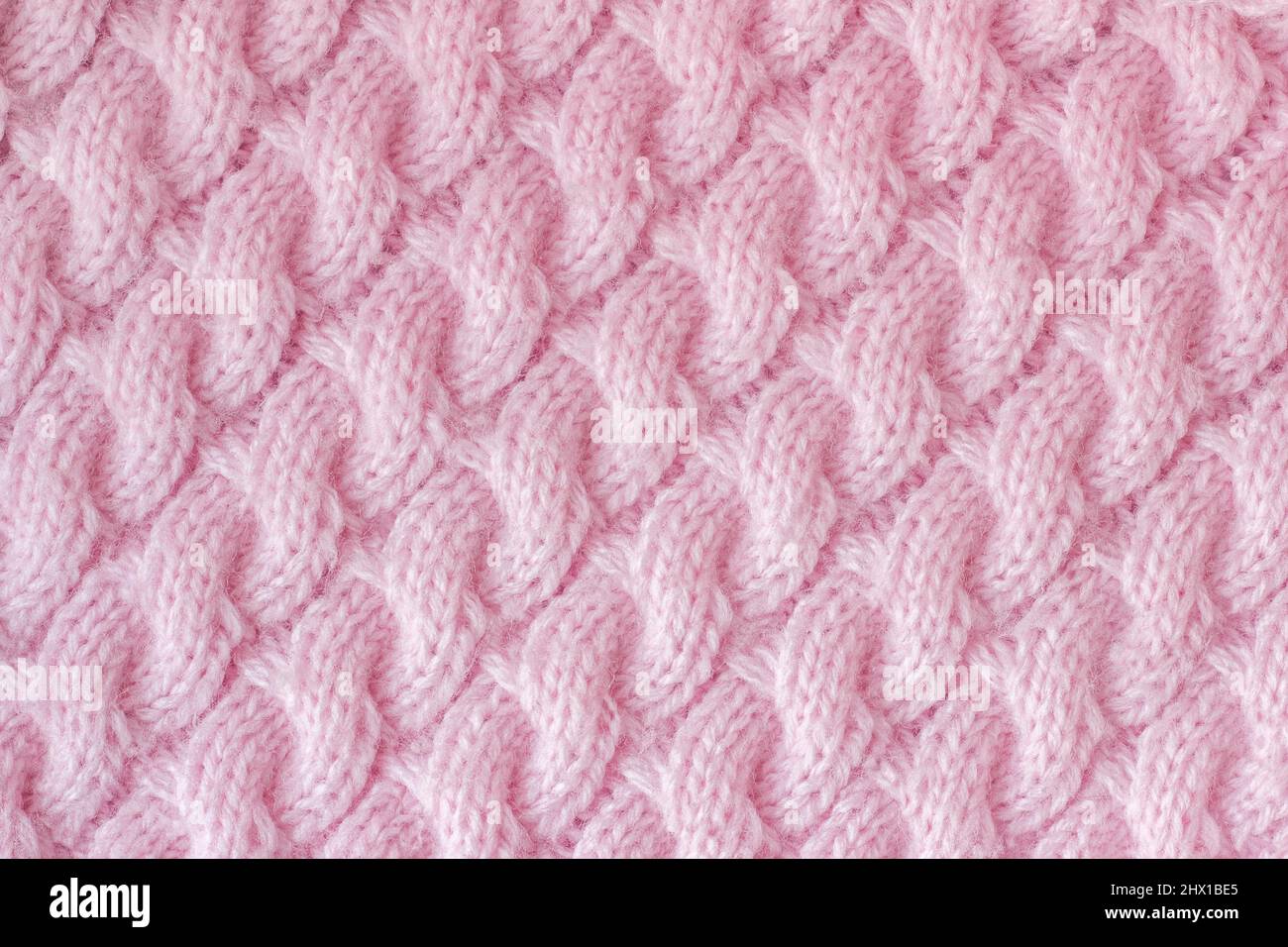 Strickstoff aus Wollgarn rosa Farbe. Stricknadeln mit Muster „Spit“, handgefertigt. Hintergrundtextur. Stockfoto