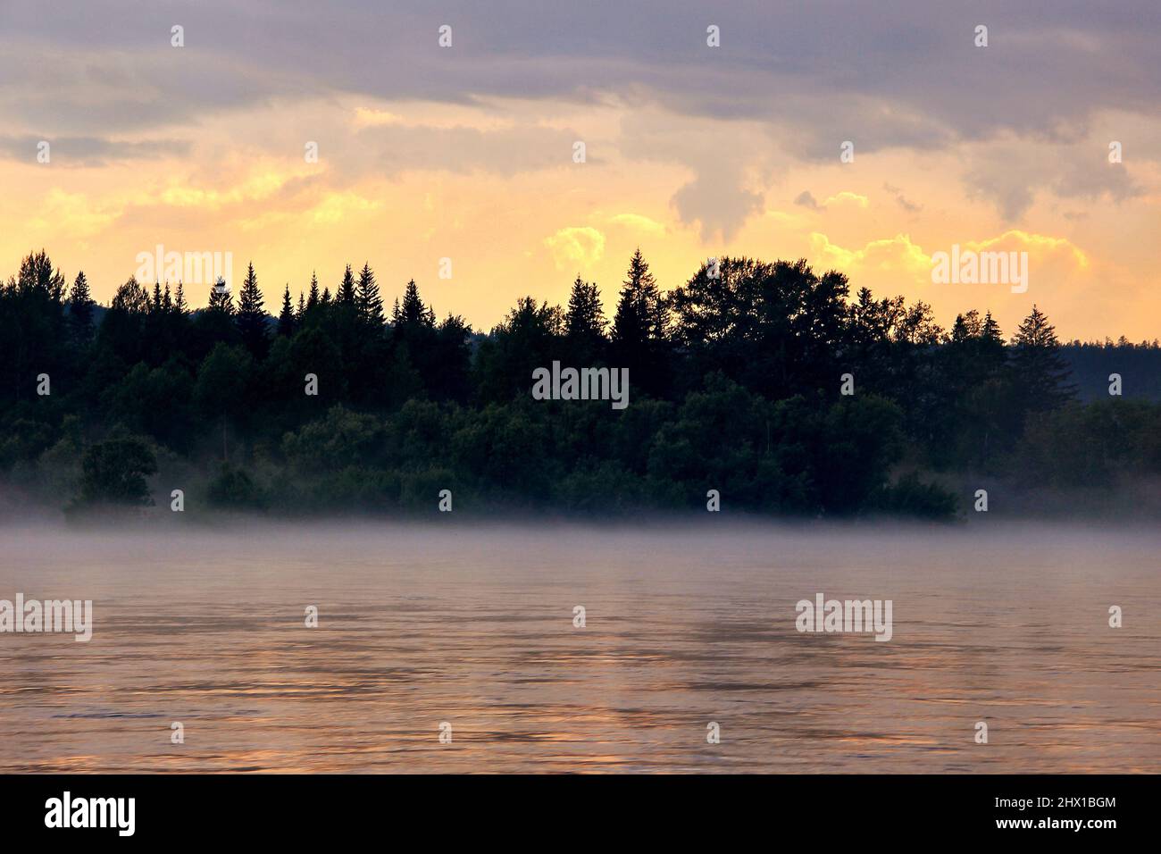 Schöner Sonnenuntergang am Fluss in Sibirien an einem Sommerabend. Nebel über dem Fluss in der Taiga, Russland Stockfoto