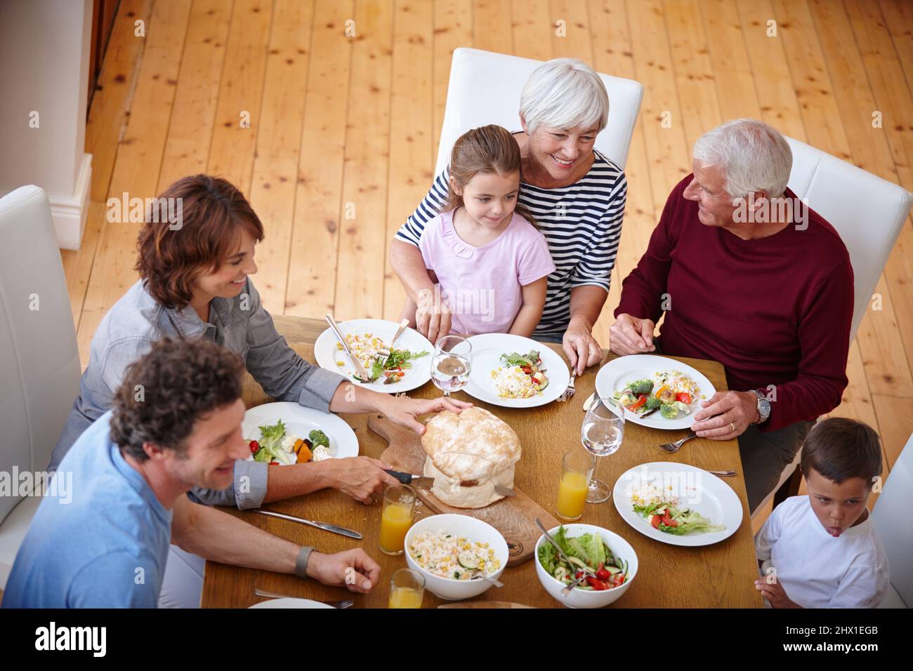 Essen und Lächeln. Aufnahme einer Familie mit mehreren Generationen, die gemeinsam eine Mahlzeit gemeinsam hat. Stockfoto