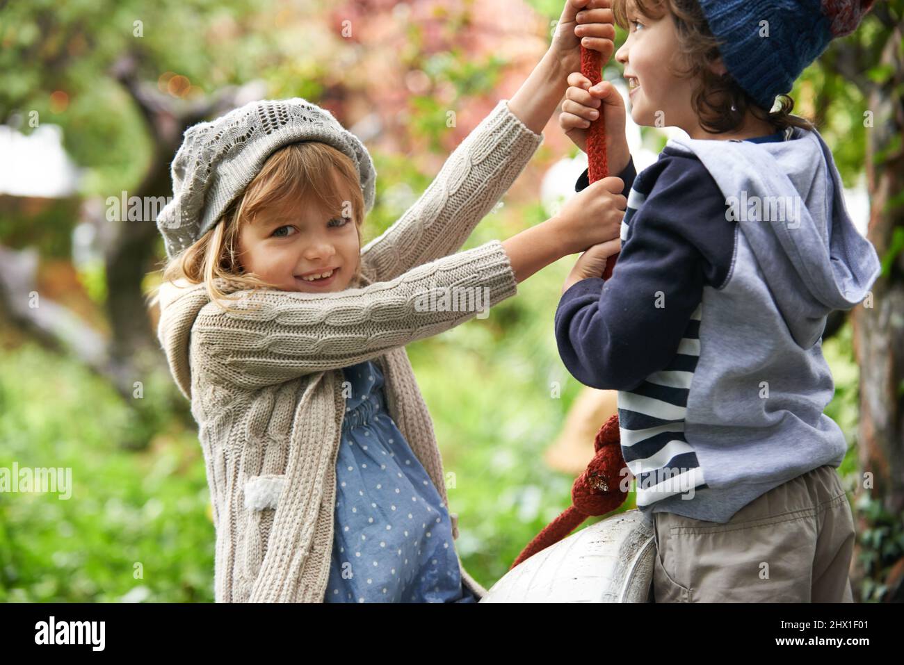 Spaß mit meinem Bruder. Aufnahme von zwei niedlichen Kindern, die in ihrem Garten auf Reifenschaukeln spielen. Stockfoto