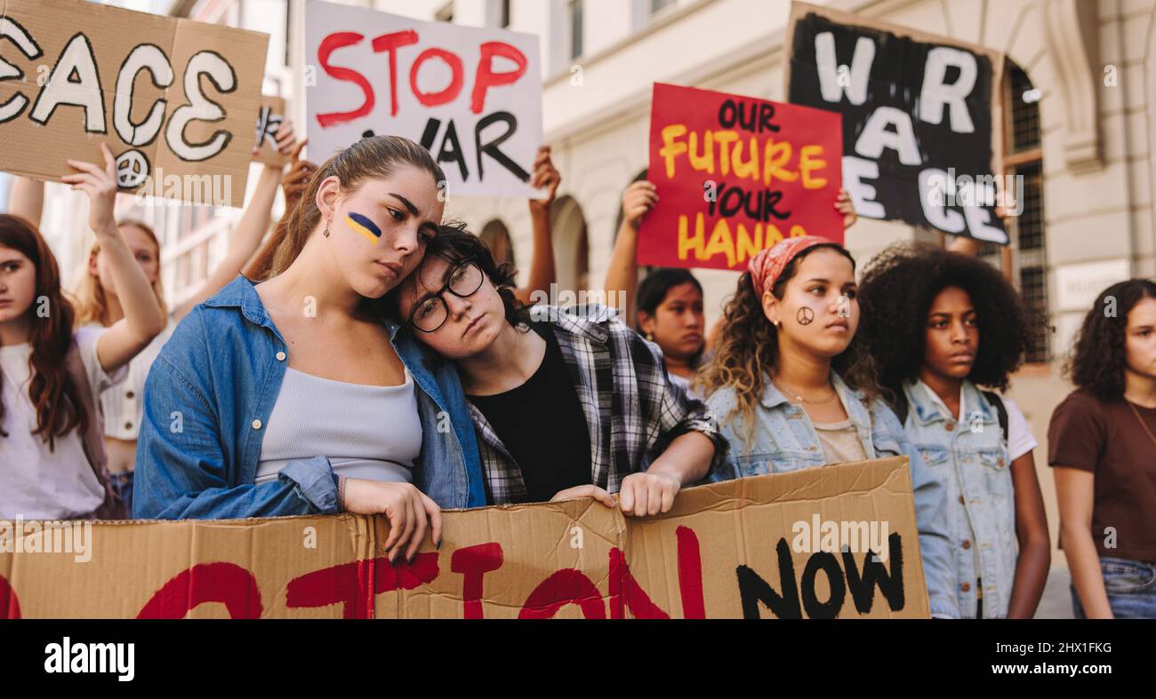 Beendet den Krieg in der Ukraine. Eine Menge multikultureller junger Menschen, die gegen den Krieg in der Ukraine marschieren. Eine Gruppe junger Protestler, die Plakate hochhalten und verbieten Stockfoto