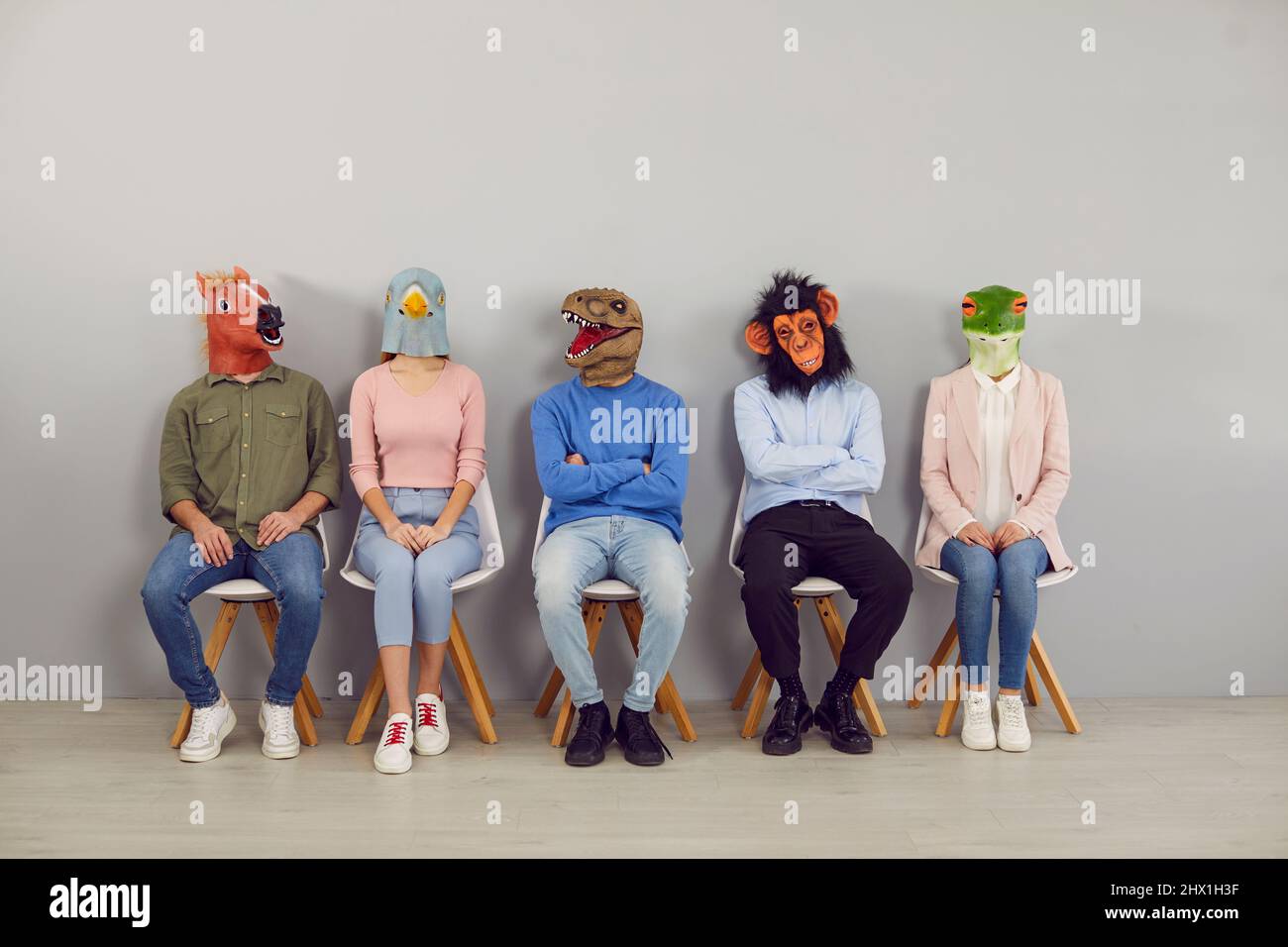 Eine Gruppe von Erwachsenen, die lustige Tiermasken tragen, wartet im Büro auf ein Vorstellungsgespräch Stockfoto