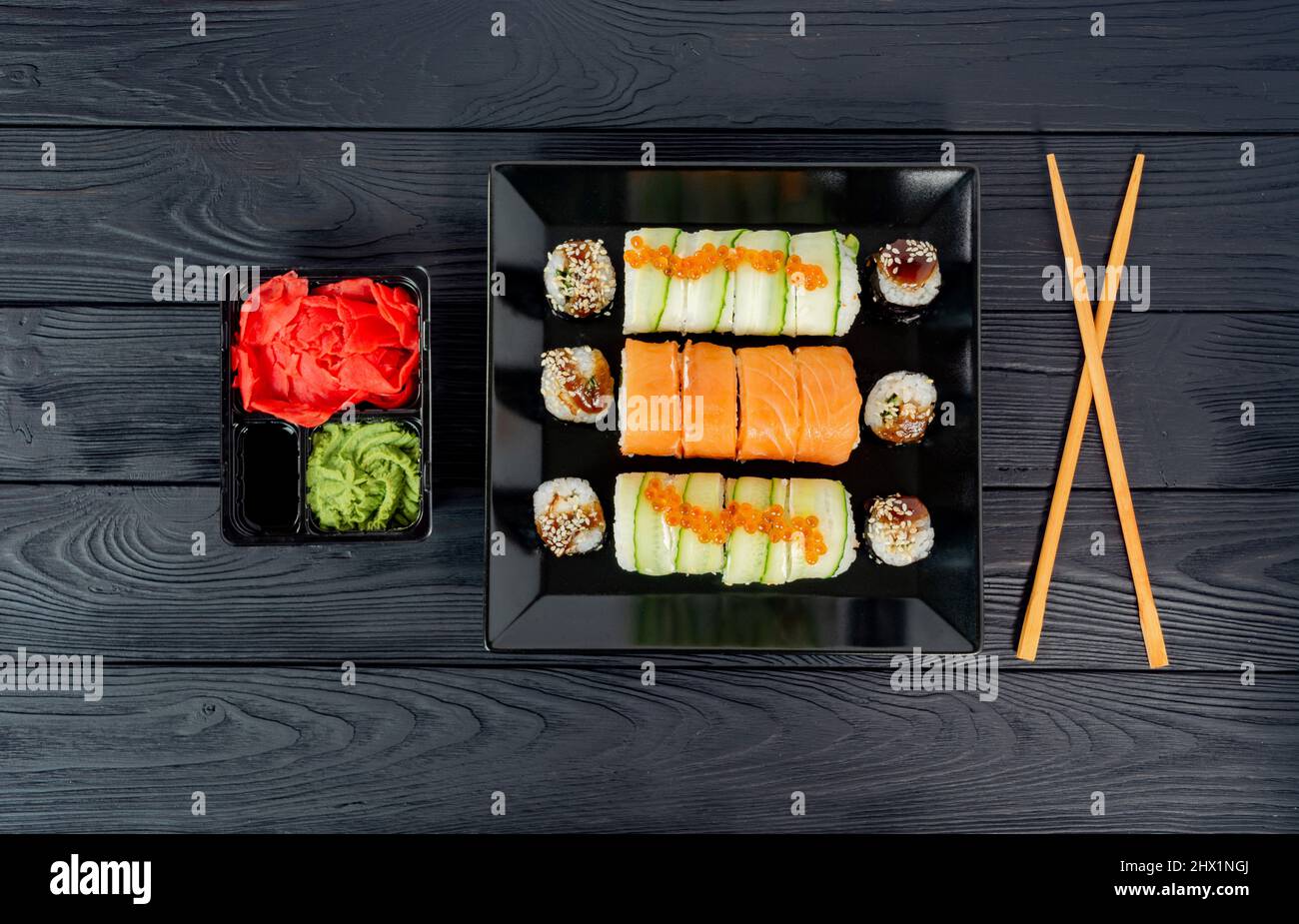 Köstliches Sushi auf einem schwarzen Teller, auf einem schwarzen Holzbrett liegen. Stockfoto