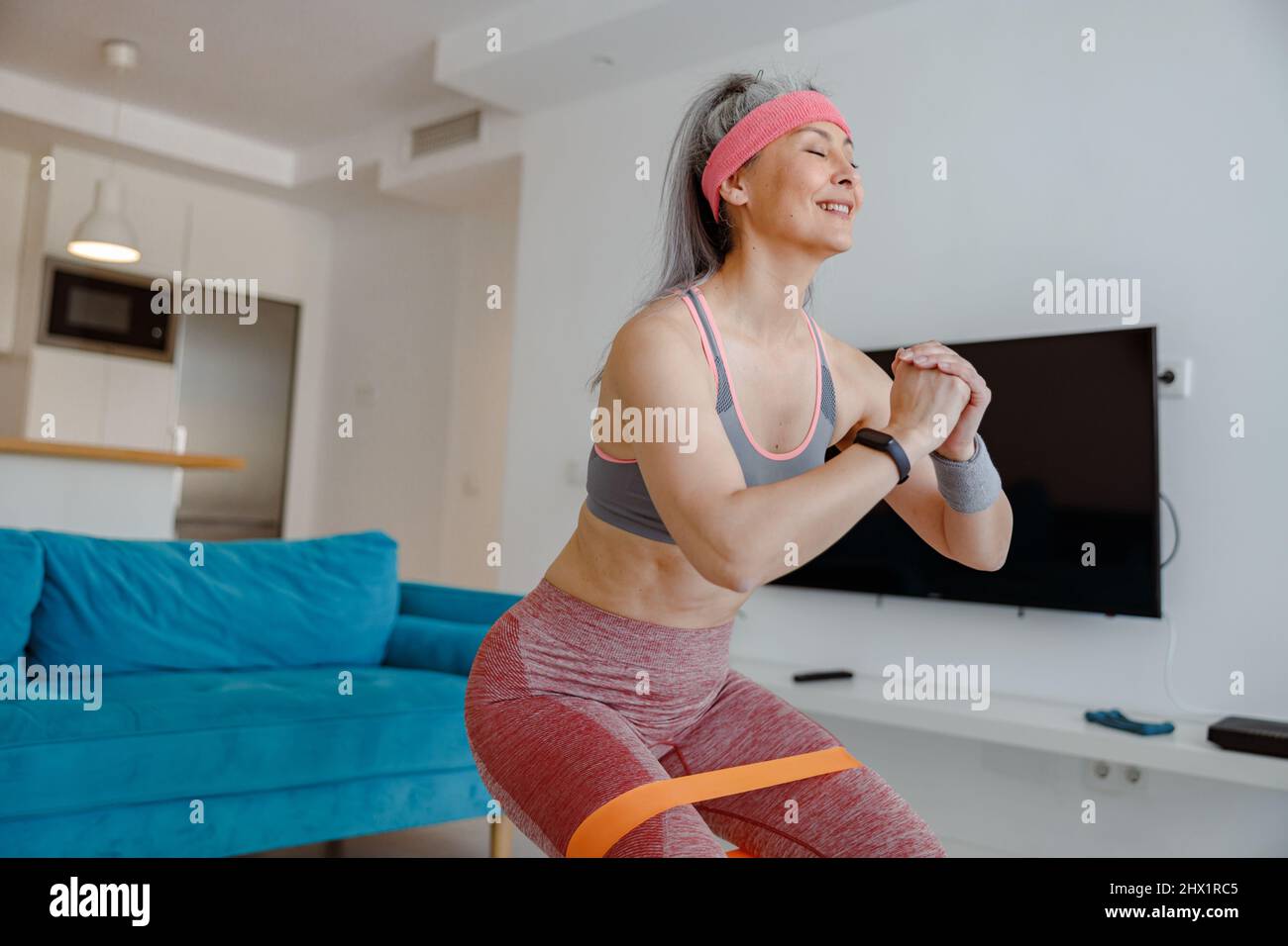 Fröhliche Frau macht Bewegung mit Widerstand Band zu Hause Stockfoto