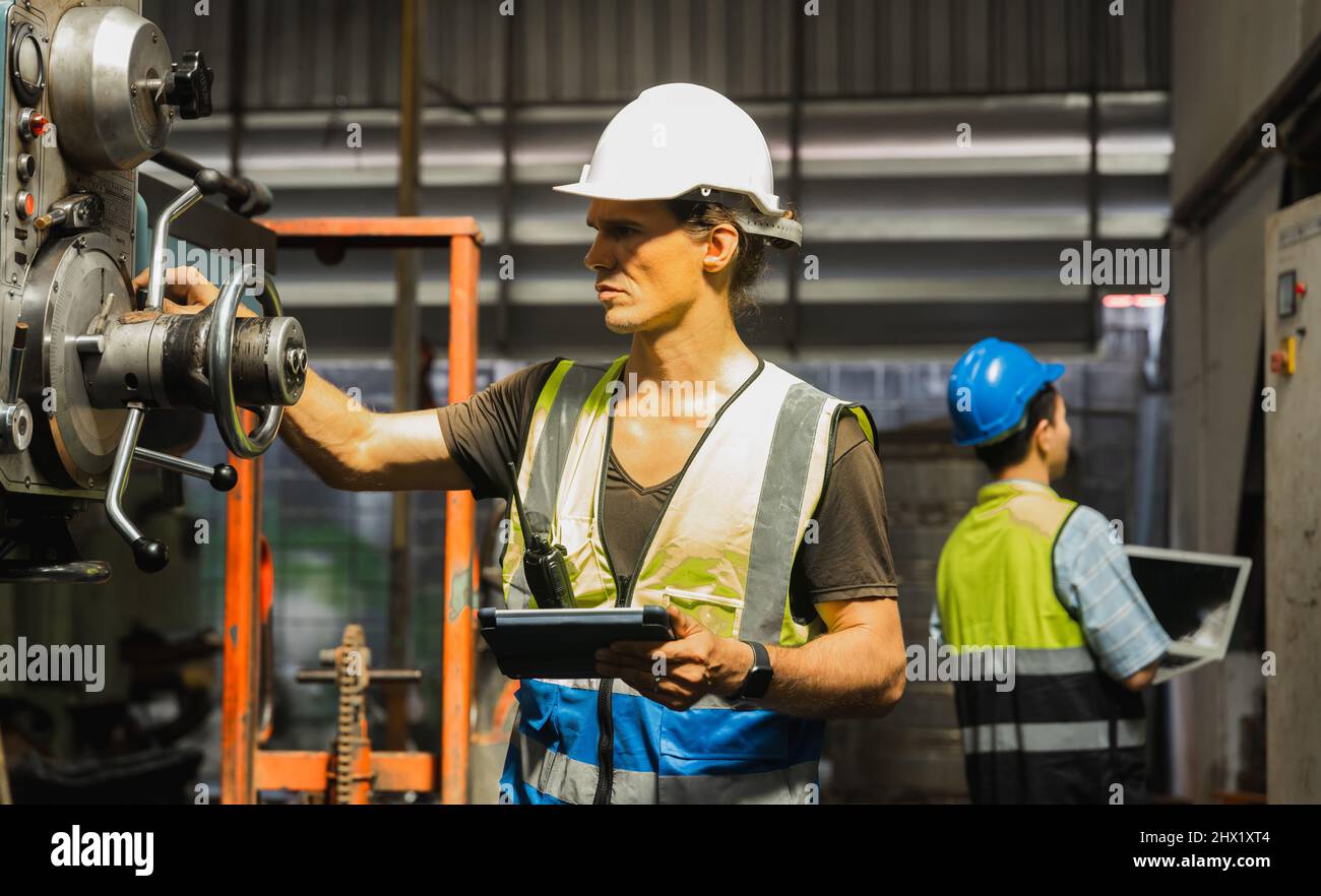 Ingenieur in reflektierender Kleidung schaut durch ein ringförmiges Objekt  in einer Fabrik, lizenzfreies Stockfoto