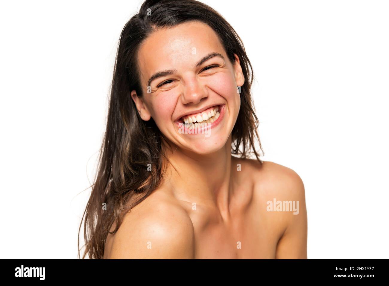Porträt einer jungen lachenden Frau ohne Make-up auf weißem Hintergrund Stockfoto