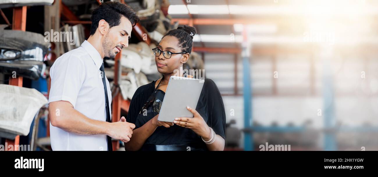 Ein Geschäftsmann spricht mit einer Sekretärin oder einem amerikanischen Arbeiter oder plant mit einem Kollegen in der Werkstatt für alte Autoteile Stockfoto