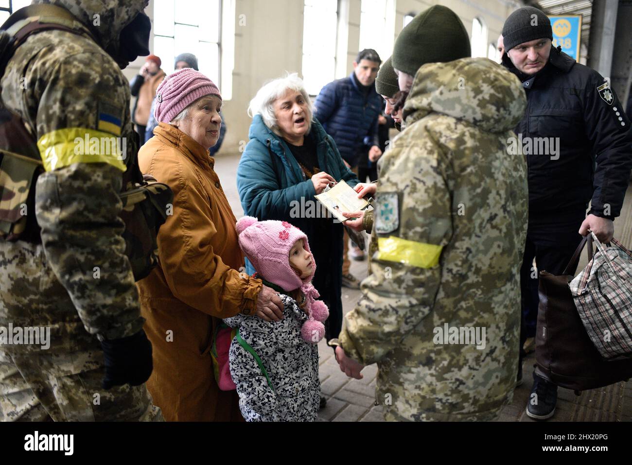 LVIV, UKRAINE - 28. FEBRUAR 2022 - zwei ältere Frauen und ein Kind sprechen mit Soldaten auf dem Bahnhof von Lviv, als Flüchtlinge vor den Feindseligkeiten an Bord der ev Stockfoto