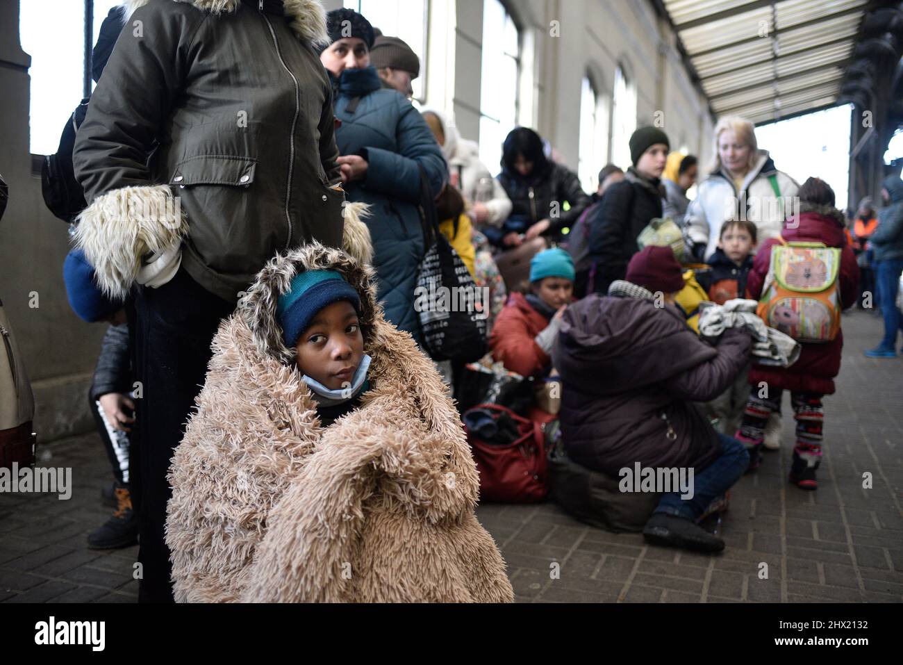 LVIV, UKRAINE - 28. FEBRUAR 2022 - Ein in eine Decke gehülltes Kind sitzt am Bahnhof von Lviv, als Flüchtlinge vor Feindseligkeiten an Bord der Evakuierung tra gehen Stockfoto