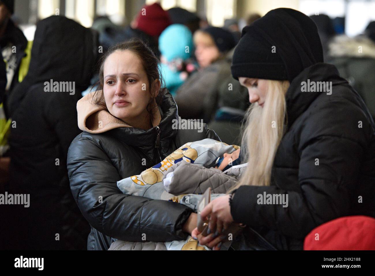 LVIV, UKRAINE - 28. FEBRUAR 2022 - Eine Frau hält am Bahnhof von Lviv ein Baby, als Flüchtlinge vor Feindseligkeiten in Evakuierungszügen nach Polen einsteigen Stockfoto