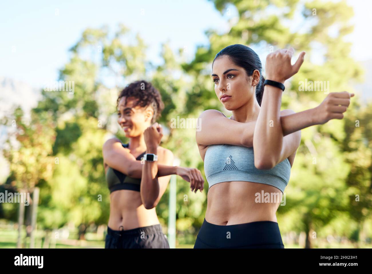 Sorgen Sie dafür, dass wir morgen nicht steif sind. Eine kurze Aufnahme von zwei attraktiven jungen Frauen, die sich tagsüber im Park nebeneinander strecken. Stockfoto