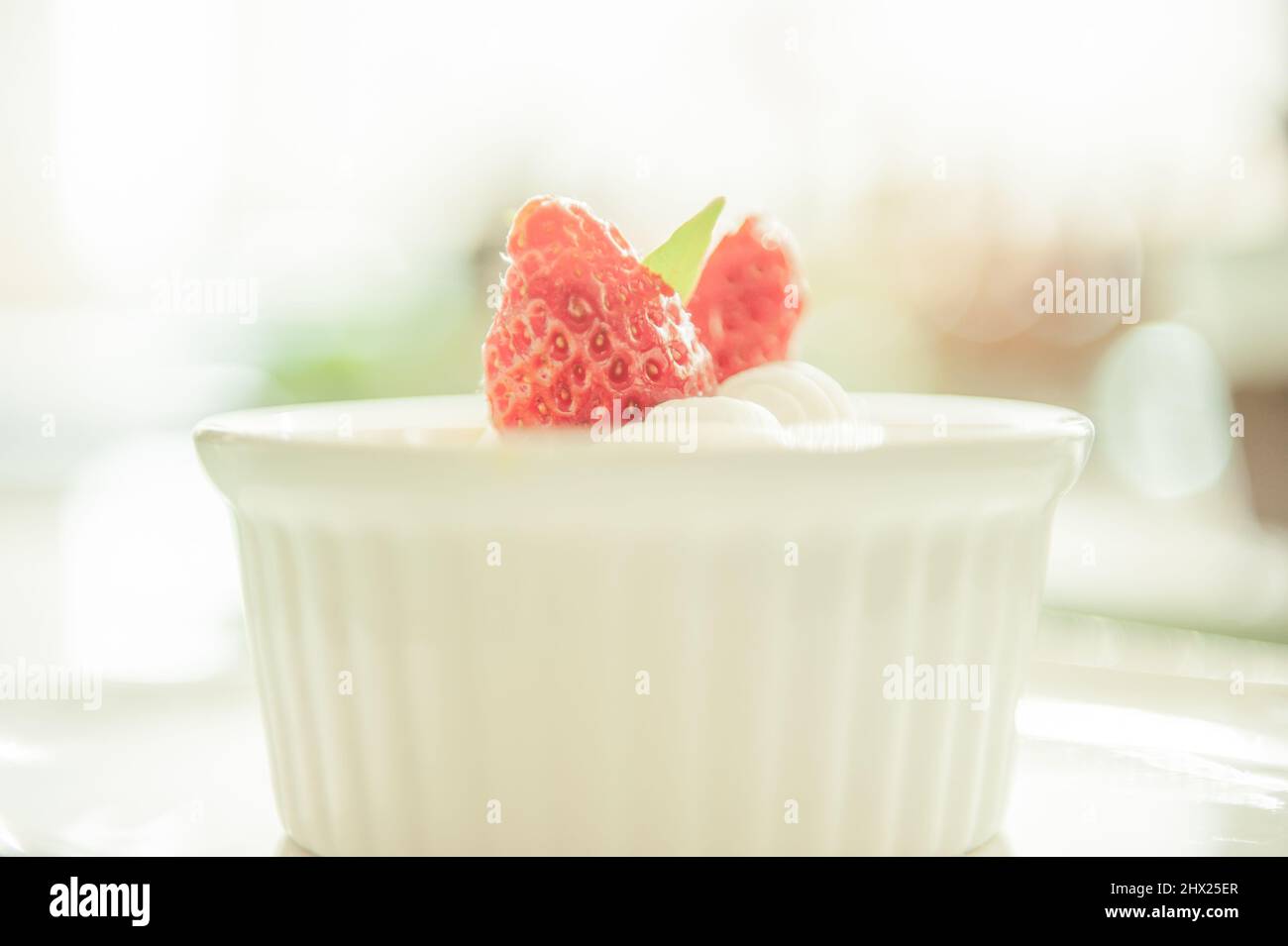 crème Brulee oder Burnt Cream mit Erdbeere auf einer weißen Tasse, weiß verschwommen im Hintergrund. Nahaufnahme. Stockfoto