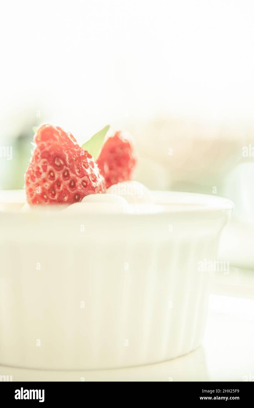crème Brulee oder Burnt Cream mit Erdbeere auf einer weißen Tasse, weiß verschwommen im Hintergrund. Nahaufnahme. Stockfoto