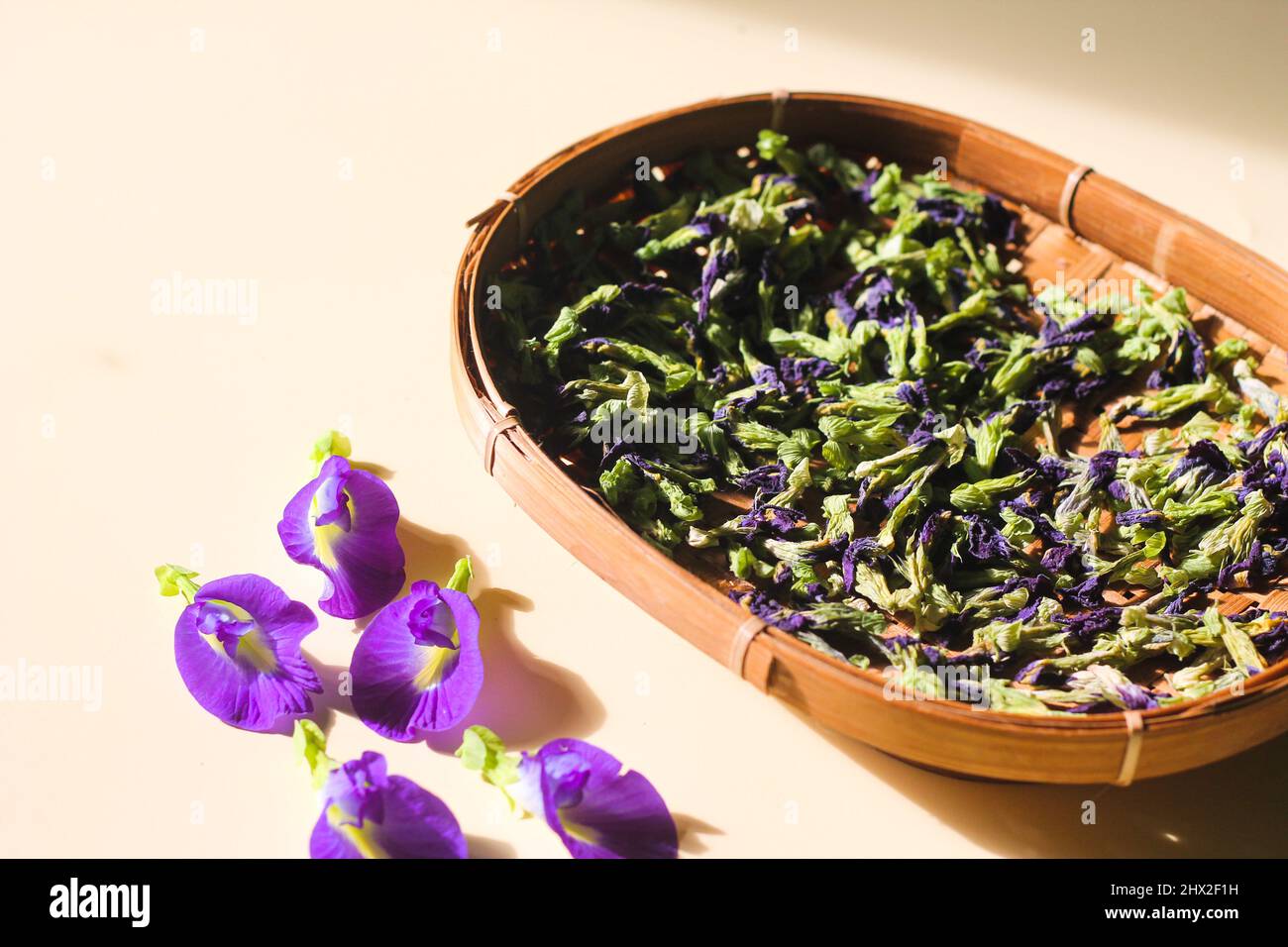 Bona Telang Kering oder getrocknete Butterfly Pea Blumen auf gewebtem Bambusblech. Isolierter Hintergrund. Stockfoto