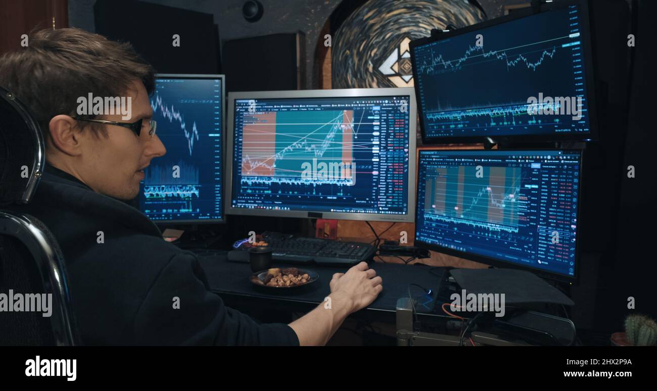 Männliche Händler, Freiberufler an der Börse, tradet Optionen und isst Nüsse Stockfoto